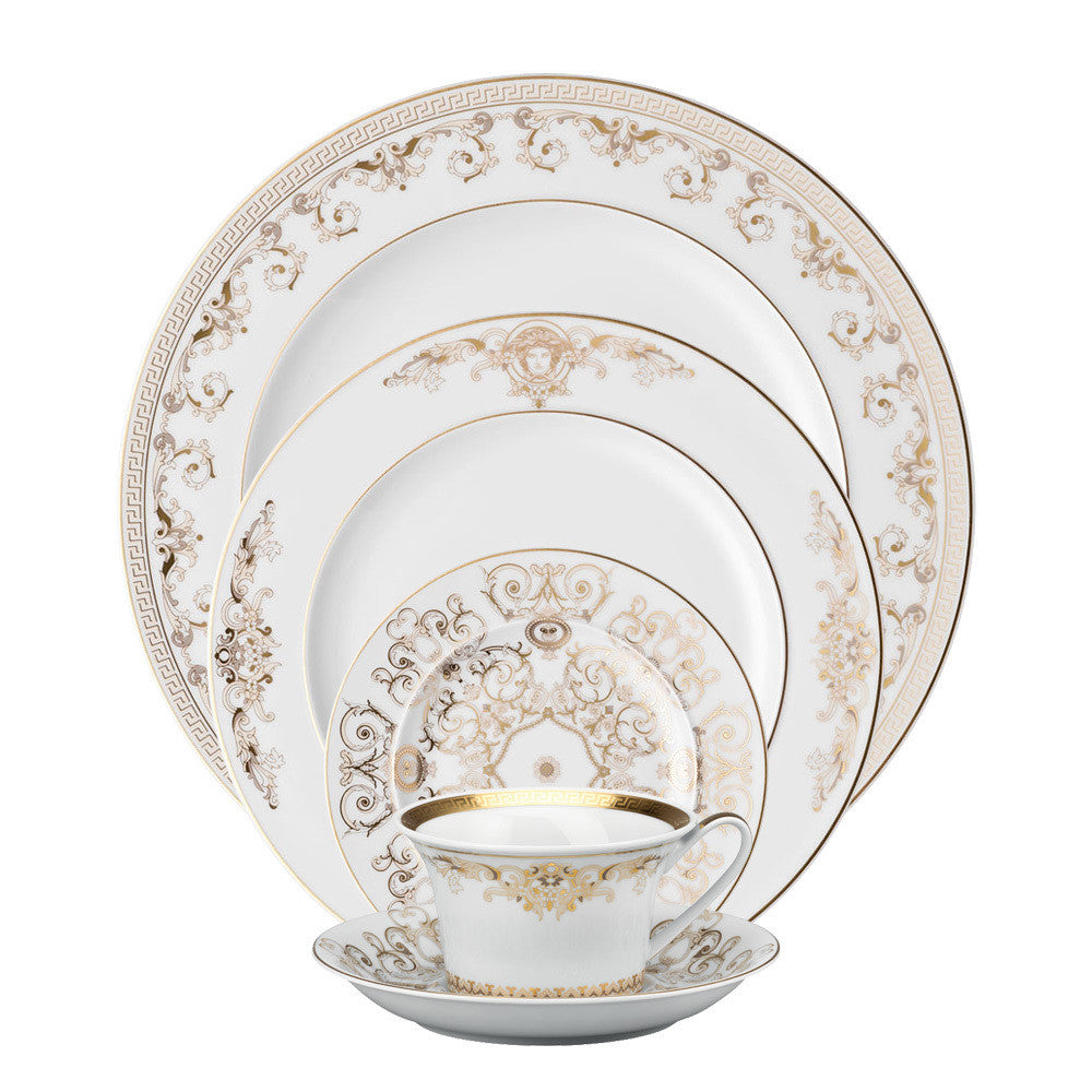 A 5-piece Versace Medusa Gala porcelain dinnerware set, including a cup and plates with gold decorations, displayed against a white background.